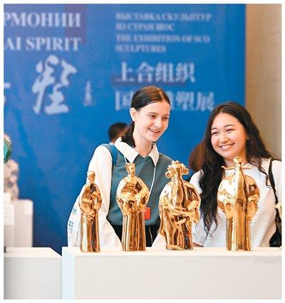 图为7月23日，在2025上合组织国家文明对话活动中，两名青年在“合光共塑”上合组织国家雕塑展上参观。