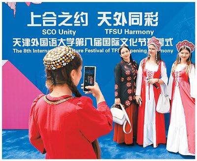 图为4月20日，中外青年在以“上合之约 天外同彩”为主题的天津外国语大学第八届国际文化节上合影留念。